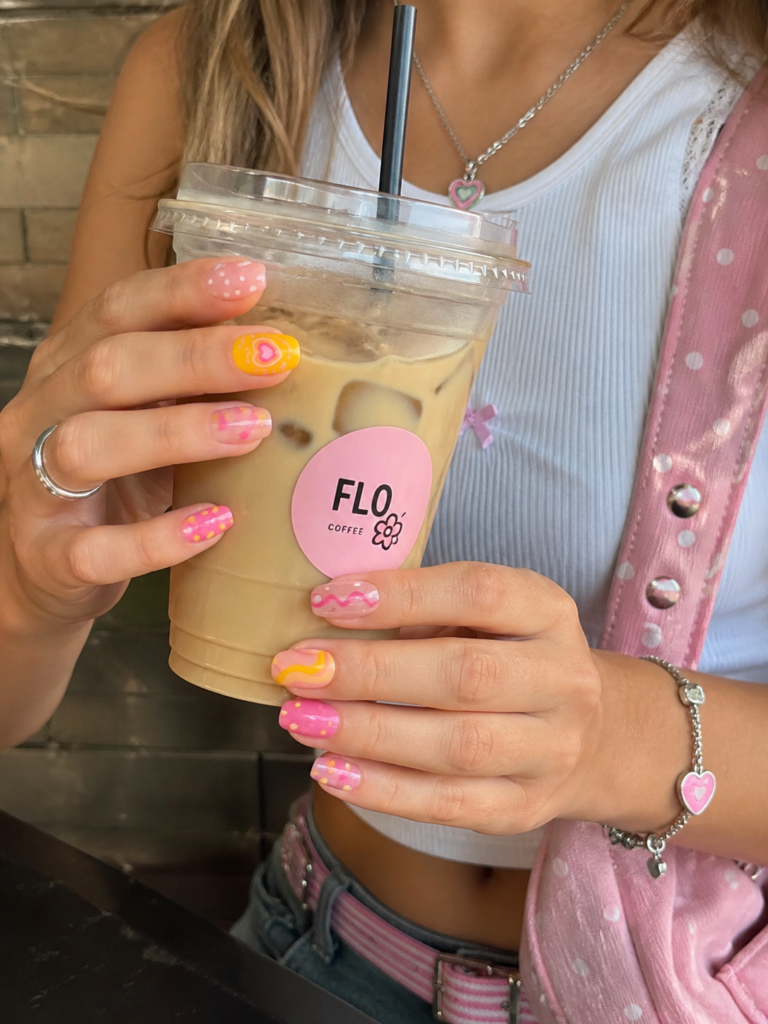 person holding drink showing colorful pink and yellow polka dot nails