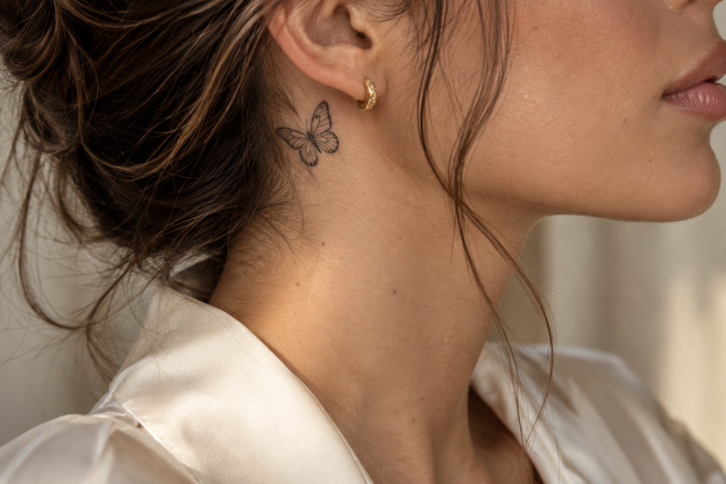 Fine-line butterfly neck tattoo in a minimalist style